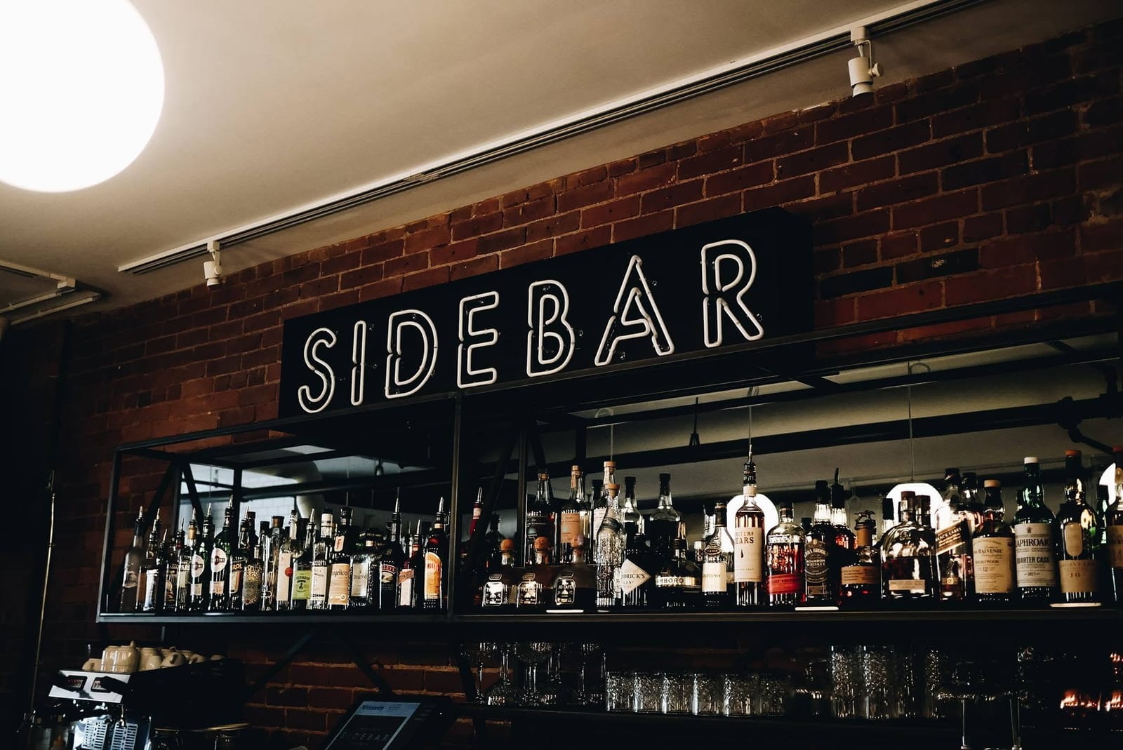 The Sidebar sign lit over the back bar and its shelves of bottles