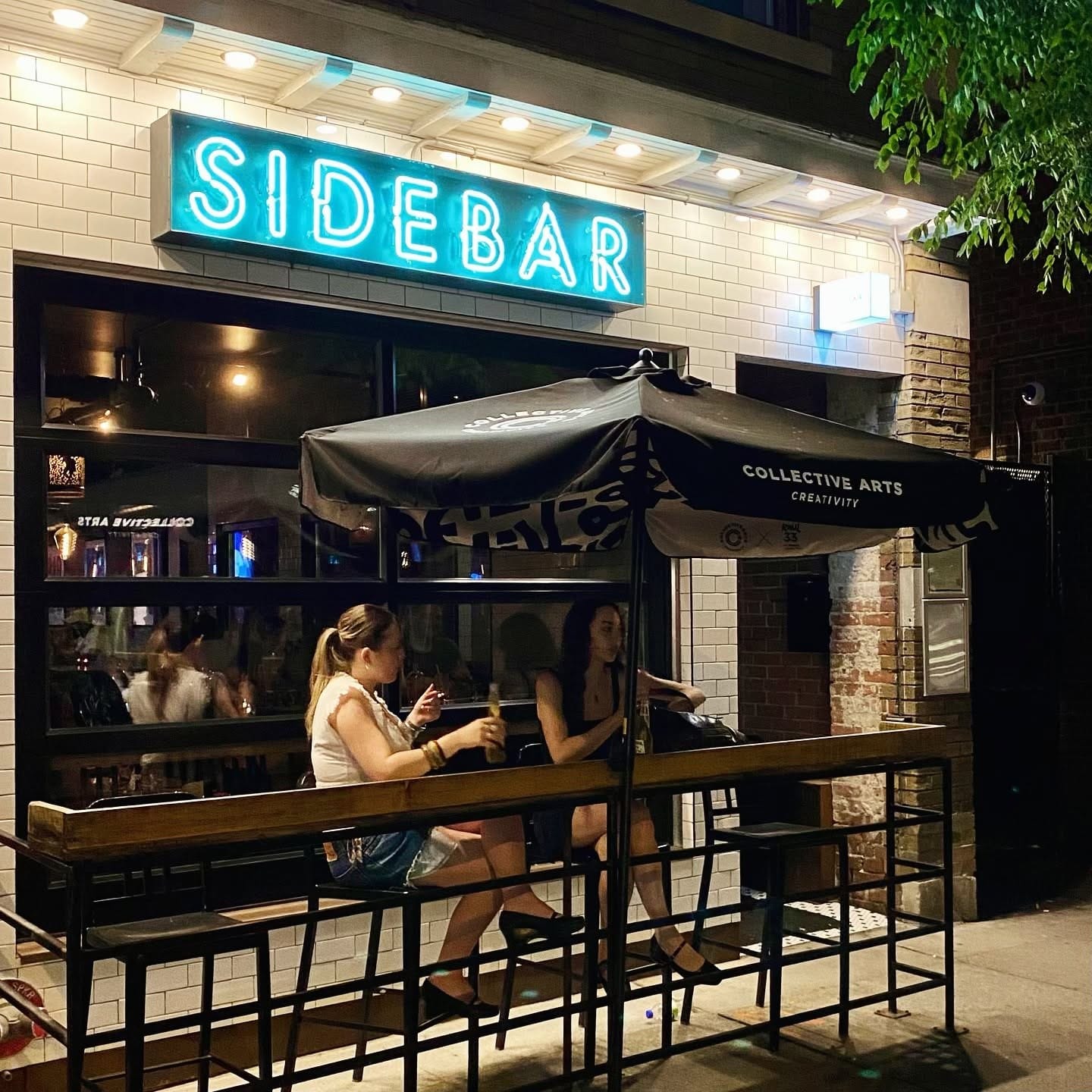 The Sidebar front with its patio and umbrella, guests sitting outside
